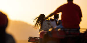 A group of friends riding ATVs through rugged terrain kicking up dust and enjoying the thrill of adventure